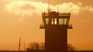Silhouette di una torre di controllo su uno sfondo di cielo al tramonto.
