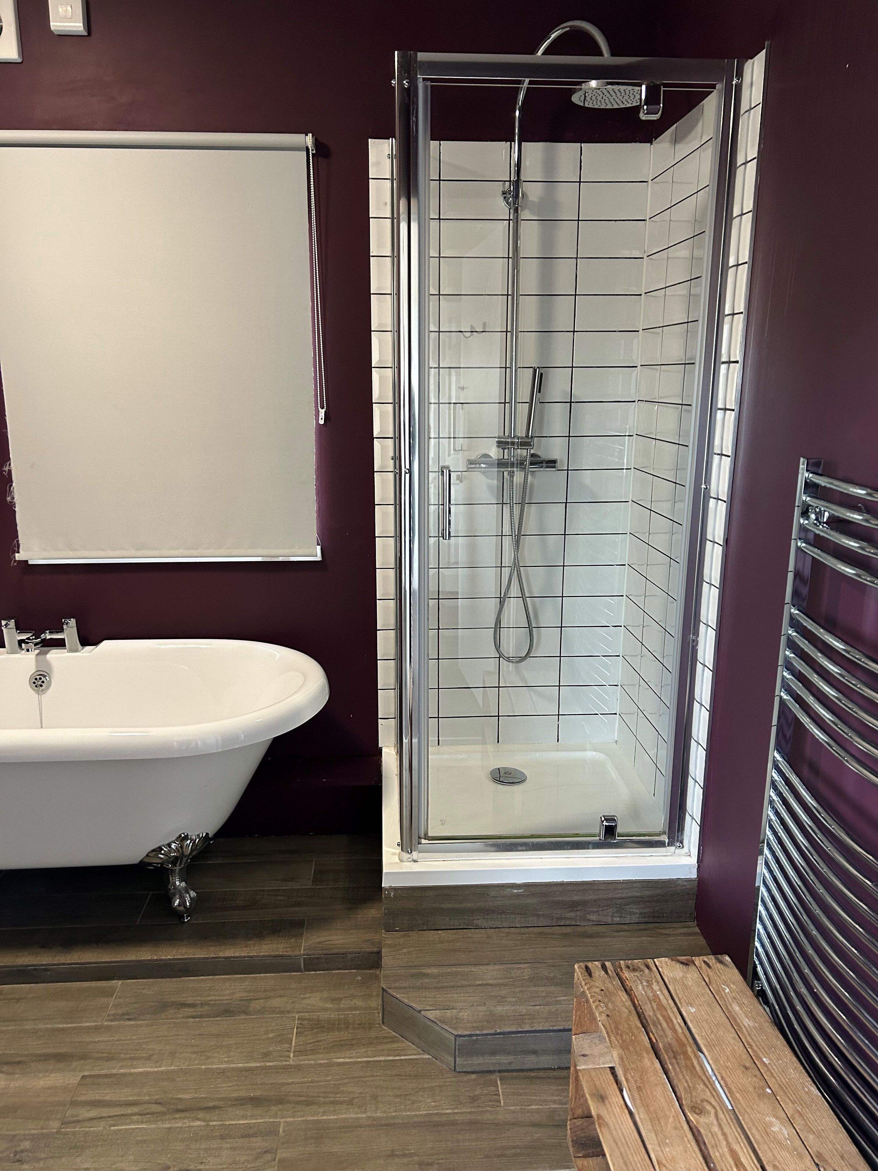 Une salle de bain avec une baignoire sur pieds, une douche à parois de verre et un banc en bois.