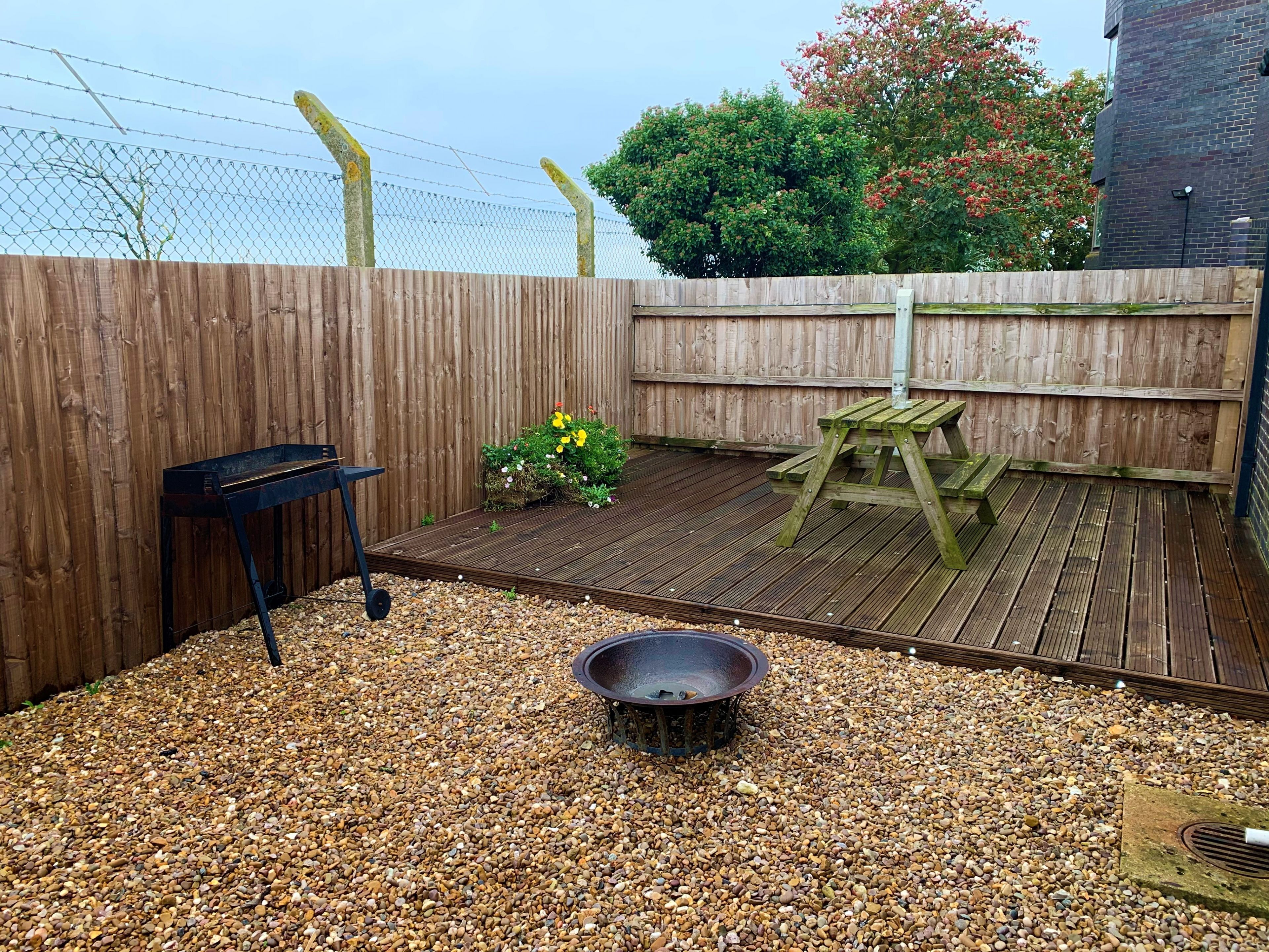 A wooden deck with a barbecue grill, a fire pit, and a picnic table.