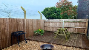 A wooden deck with a barbecue grill, a fire pit, and a picnic table. - Spitfire - 2 bedroom apartment (Friskney)