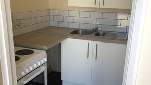 A compact kitchen with white cabinets, a double sink, and a stove. - Glamping pod helicopter (Friskney)