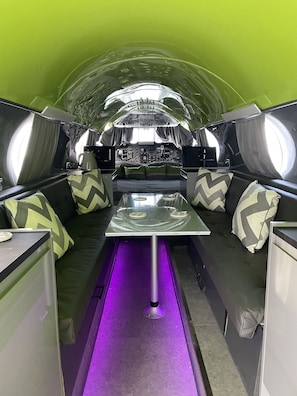 A compact, modern interior with a central table, cushioned seating, and a control panel. - Aeroplane - Jetstream (Boston)