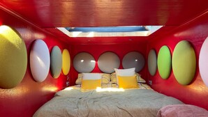 Ein Zimmer mit einem Bett, einer Dachfensterkuppel und runden Wandverzierungen.