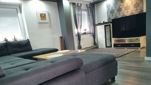 A modern living room with a grey sectional sofa, a wooden coffee table, and a flat-screen TV on a stand. - Haus in Ruhiger Lage (Bad Fallingbostel)