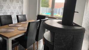 A dining area with a round table, black chairs, and a stone stove. - Haus in Ruhiger Lage (Bad Fallingbostel)