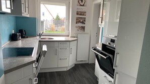 A modern kitchen with a built-in oven, a sink, and a window with a view of the outside. - Haus in Ruhiger Lage (Bad Fallingbostel)