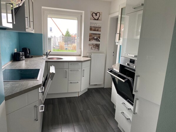 A modern kitchen with a built-in oven, a sink, and a window with a view of the outside.