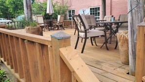 Una terraza al aire libre con barandas de madera, una mesa con sillas y una planta en maceta.