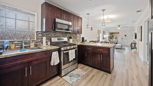 A modern kitchen with dark wood cabinets, a stainless steel stove, and a large window.