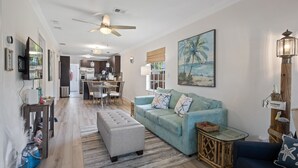 A spacious living room with a light blue sofa, a wooden coffee table, and a dining area in the background.