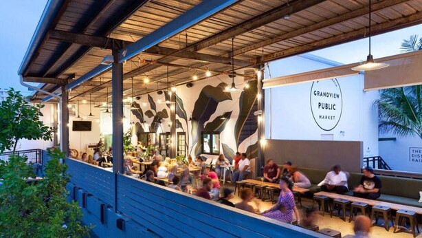 A restaurant with a covered outdoor seating area, a mural on the wall, and a sign for Grandview Public Market.
