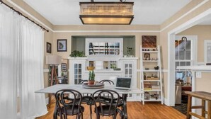 A dining area with a table and chairs, a laptop, and a bookshelf. - 2Bd Bungalow with backyard sauna, by Alberta Arts (Portland)