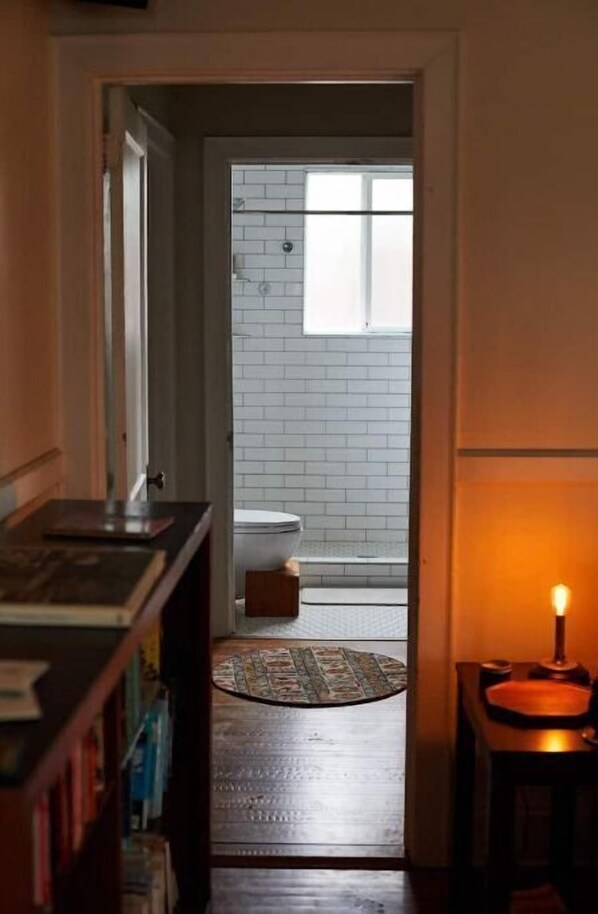 A narrow hallway leading to a bathroom with a toilet and a window.
