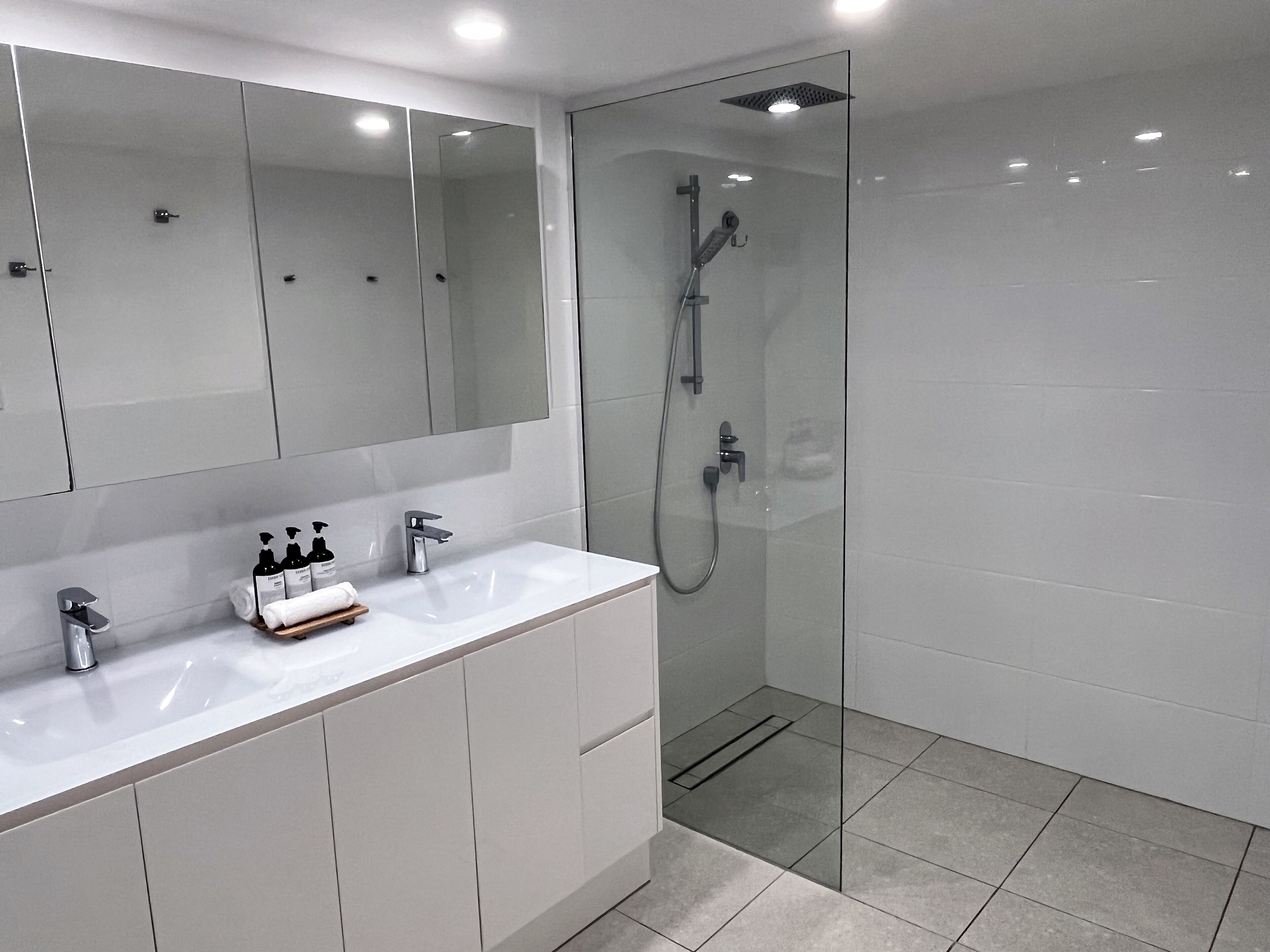 A modern bathroom with a glass-enclosed shower, a white vanity with a mirror, and a sink.
