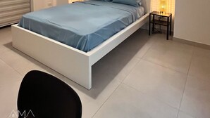 Een moderne slaapkamer met een bed, nachtlampjes en een klein tafeltje.