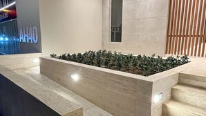 Een moderne receptie met een marmeren receptiebalie, een houten lamelwand en een betegelde vloer.
