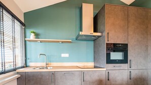 A modern kitchen with grey cabinets, a stainless steel sink, and a built-in oven. - Charming House With Garden (Hellendoorn)