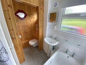 Bathroom features a toilet, sink, and bathtub with a window offering an outdoor view.