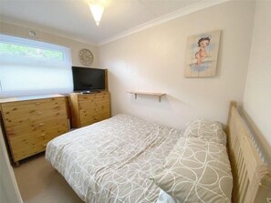 Cozy retreat with a single bed, dresser, and TV.