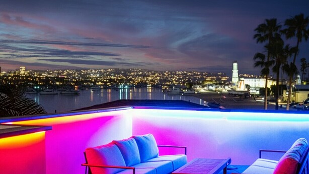 An outdoor pool area with seating and a view of a cityscape at night.