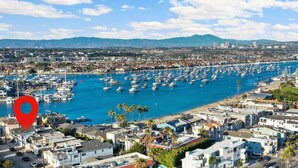 A coastal cityscape with a marina filled with boats, residential buildings, and a clear blue sky.
