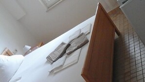 Une chambre d’hôtel avec un lit, une tête de lit en bois et un sol carrelé.