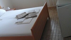 Un lit bien fait, avec des oreillers et des serviettes pliées, une table de chevet avec une lampe et une fenêtre avec des rideaux.