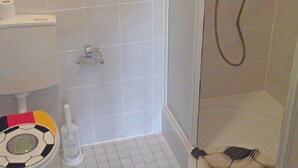 Une salle de bain équipée de toilettes, d’une douche et d’une brosse pour nettoyer les toilettes.