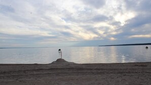 Una playa con un faro en una pequeña isla distante.