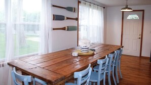 Una mesa de comedor de madera con sillas azules, una puerta blanca y tres palas de madera en la pared.
