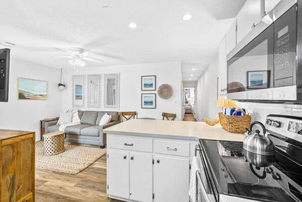 A modern kitchen with white cabinetry, a central island, and a stove.