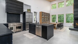 Cozinha moderna com ilha central, eletrodomésticos de aço inoxidável e máquina de lavar louça embutida.