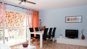 Un salon comprenant un coin repas, un téléviseur et un ventilateur de plafond.