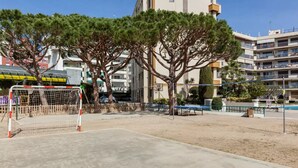 Una cancha deportiva de arena con un arco, rodeada de árboles y edificios.