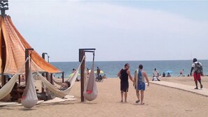 Una playa con hamacas, una sombrilla y una torre de salvavidas.