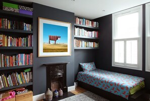Cozy retreat with a comfortable bed, bookshelf, and framed artwork.