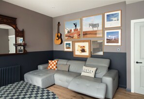 A modern living room with a grey sectional sofa, a checkered rug, and framed artwork on the wall. - Artist home - truly unique house in West London (London)