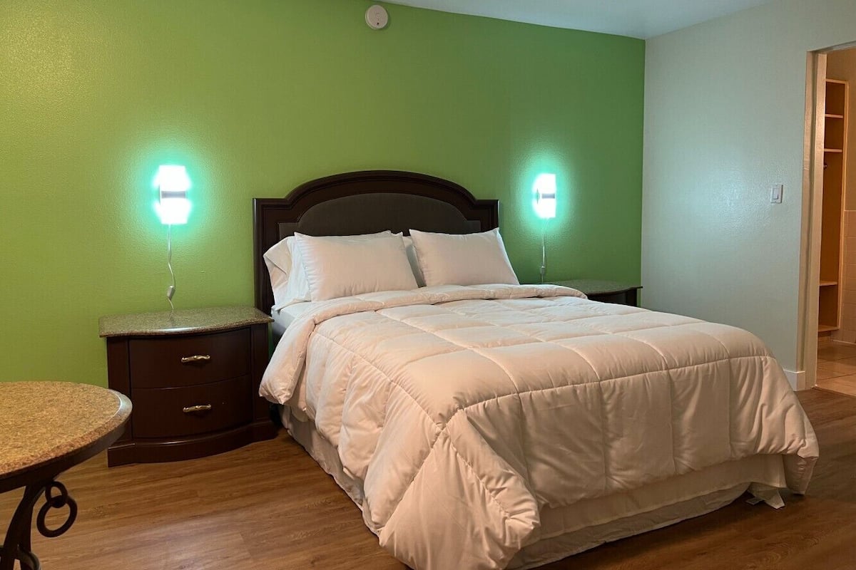 A bedroom with a bed, nightstands, a table, and green walls.