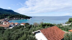 Ein Küstendorf mit terrakottafarbenen Dächern, blauem Meer und einer gebirgigen Kulisse.