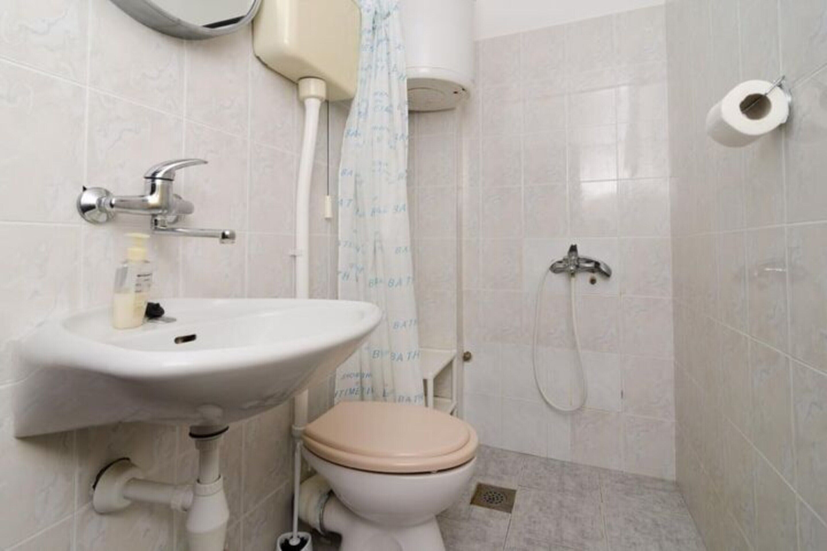 Un bagno con lavandino, WC, doccia e porta carta igienica.