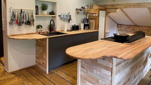 A modern kitchen with wooden countertops, a built-in island, and a variety of utensils and appliances. - Spacious Holiday Home in Mayrhofen With hot tub (Mayrhofen)