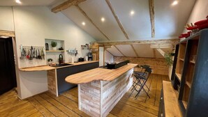 A kitchen with wooden beams, a central island, and a dining area with chairs. - Spacious Holiday Home in Mayrhofen With hot tub (Mayrhofen)