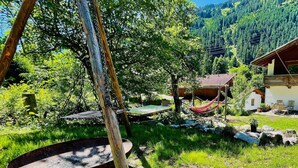 A rustic outdoor setting with a hammock, a fire pit, and a wooden cabin. - Spacious Holiday Home in Mayrhofen With hot tub (Mayrhofen)