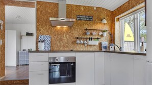 A modern kitchen with white cabinetry, a built-in oven, and a wooden backsplash. - Beautiful home in Haderslev with WiFi (Haderslev)