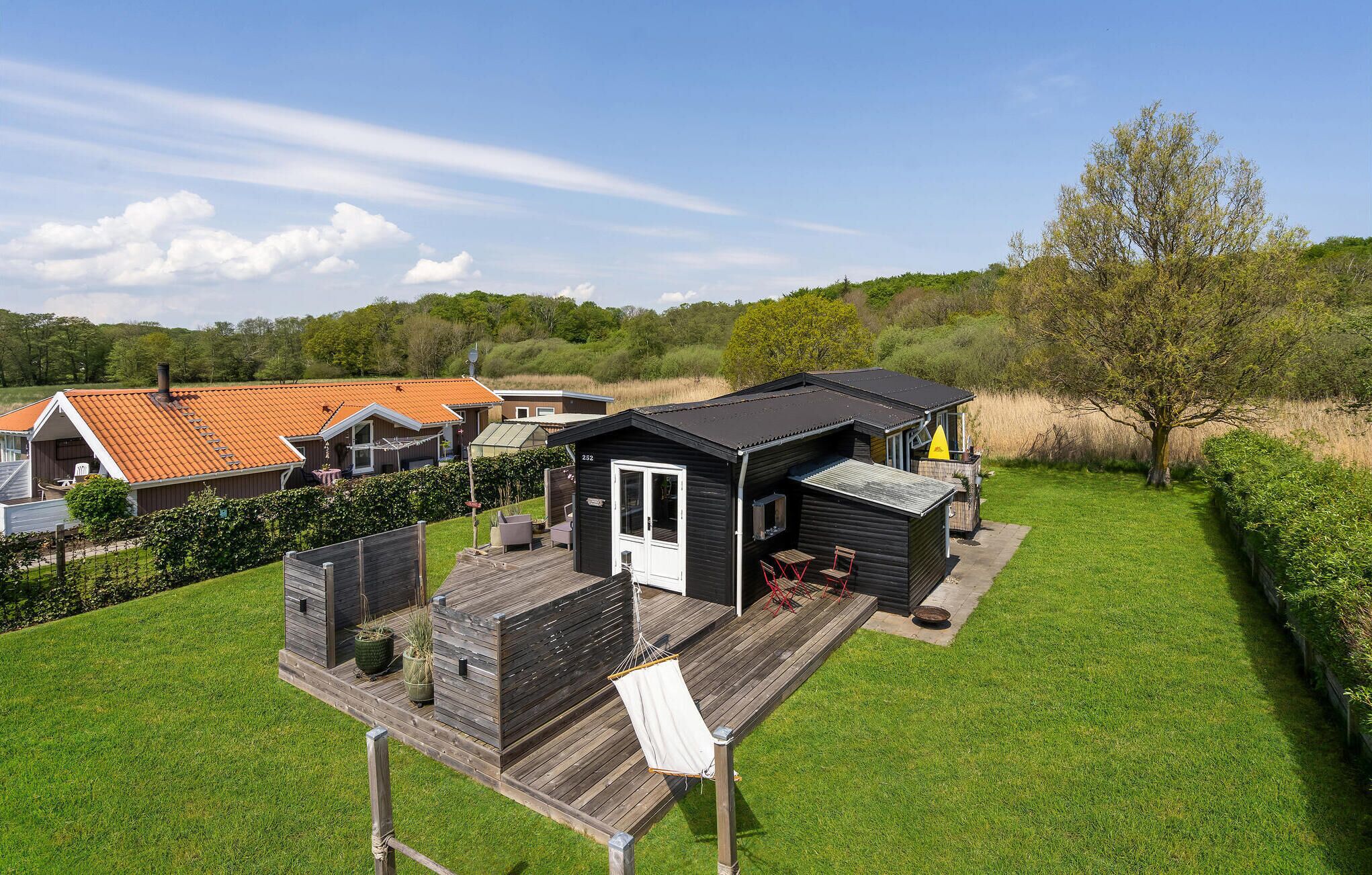 Eine Holzdielen-Terrasse mit einer kleinen Hütte, einem Essbereich und einer überdachten Sitzgelegenheit im Freien.