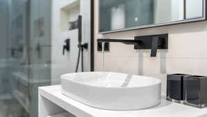 Ein modernes Badezimmer mit einem weißen Waschbecken, einem schwarzen Handtuchhalter und einem Spiegel.