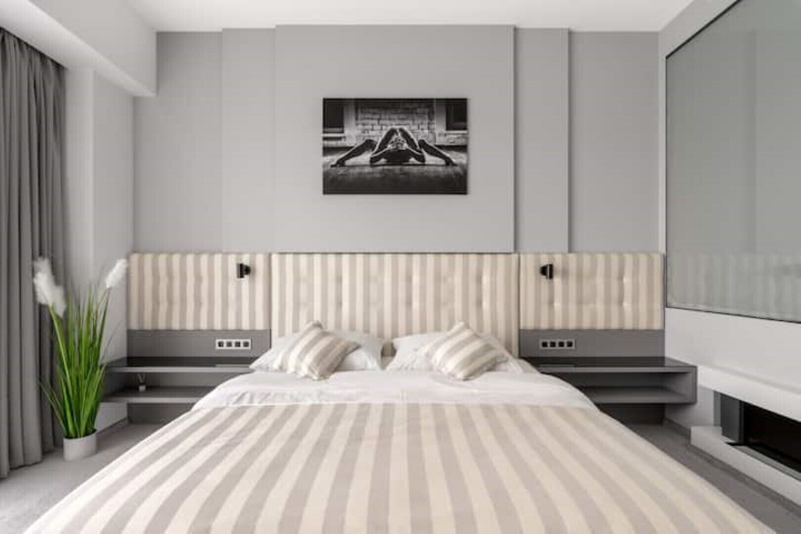 Una camera da letto moderna con un letto grande, due comodini, una TV a parete e un'ampia finestra.