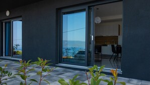 Un edificio moderno con grandes puertas correderas de vidrio que dan a una cocina con armarios blancos y encimera negra.