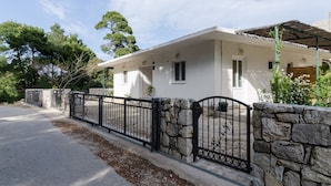 A two-story house with a stone wall and black metal fence. - Apartments Skurla - One Bedroom Apartment With Terrace (Mljet)