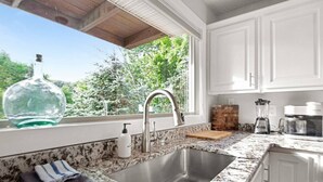 Cocina con encimera de granito, pileta de acero inoxidable y alacenas blancas.